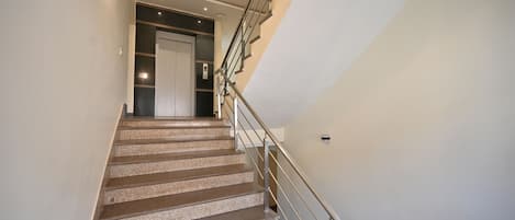 A modern staircase with a metal railing and a door at the top.