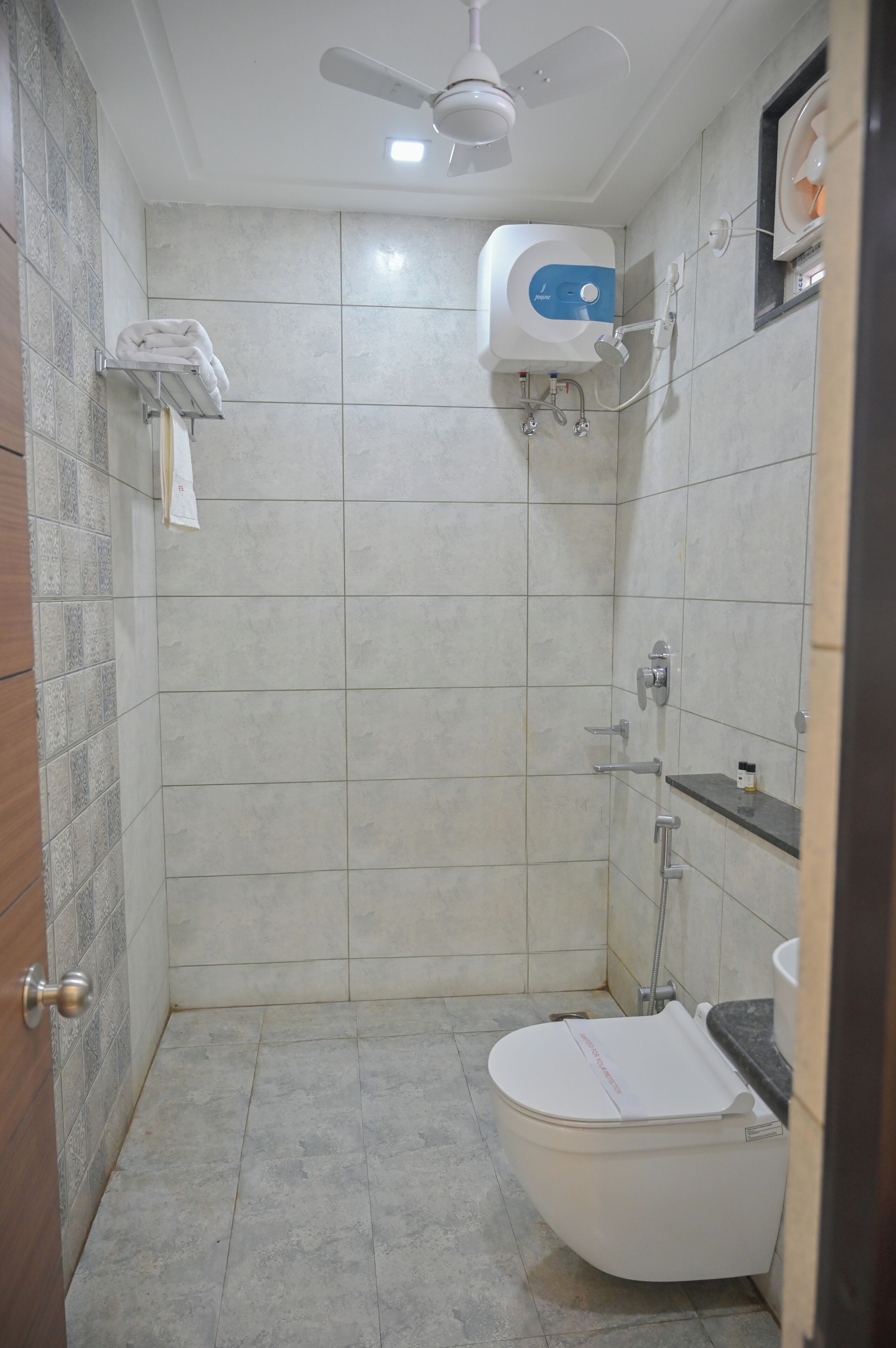A small bathroom with a toilet, a shower, and a ceiling fan.