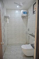 A small bathroom with a toilet, a shower, and a ceiling fan.