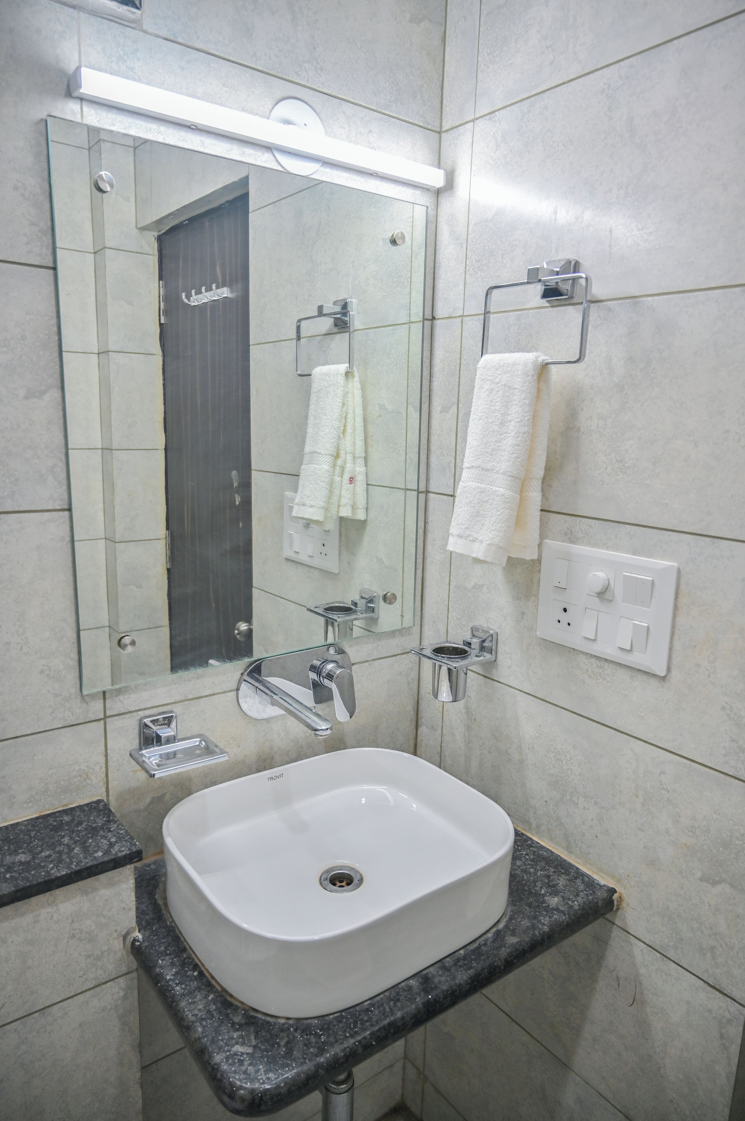 A modern bathroom with a white sink, a mirror, and a towel rack.