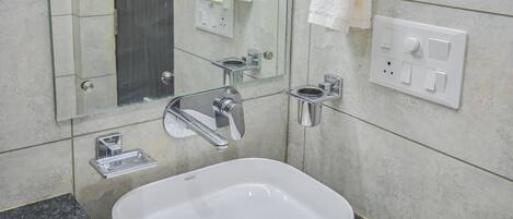 A modern bathroom with a white sink, a mirror, and a towel rack.