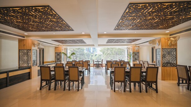 A spacious dining area with high ceilings, intricate ceiling designs, and a central view of the outdoors. - Blueberry Inn (Raipur)