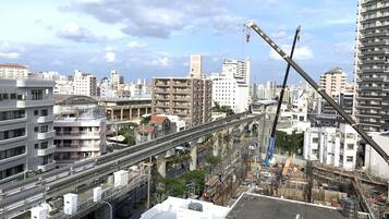 A high-rise building with multiple floors, a construction crane, and a complex network of roads and railways in the background.