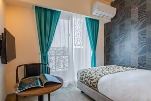 A hotel room with a bed, a chair, a table, and a window with curtains. - Mr.KINJO Miki24 in front of Makishi Station (Naha)