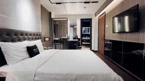 Een hotelkamer met een groot bed, een televisie, een kledingkast en een badkamer op de achtergrond.