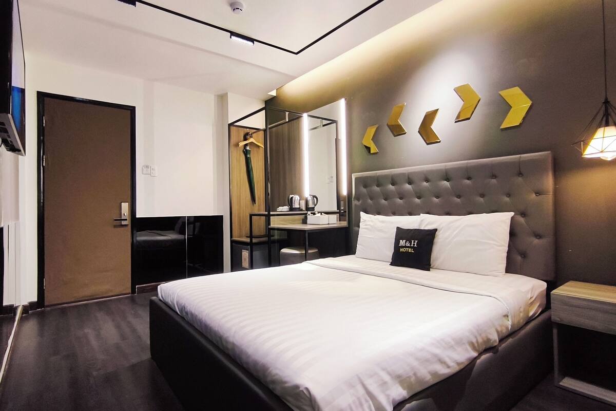 Une chambre d’hôtel avec un grand lit, une table de chevet, un miroir et une armoire.