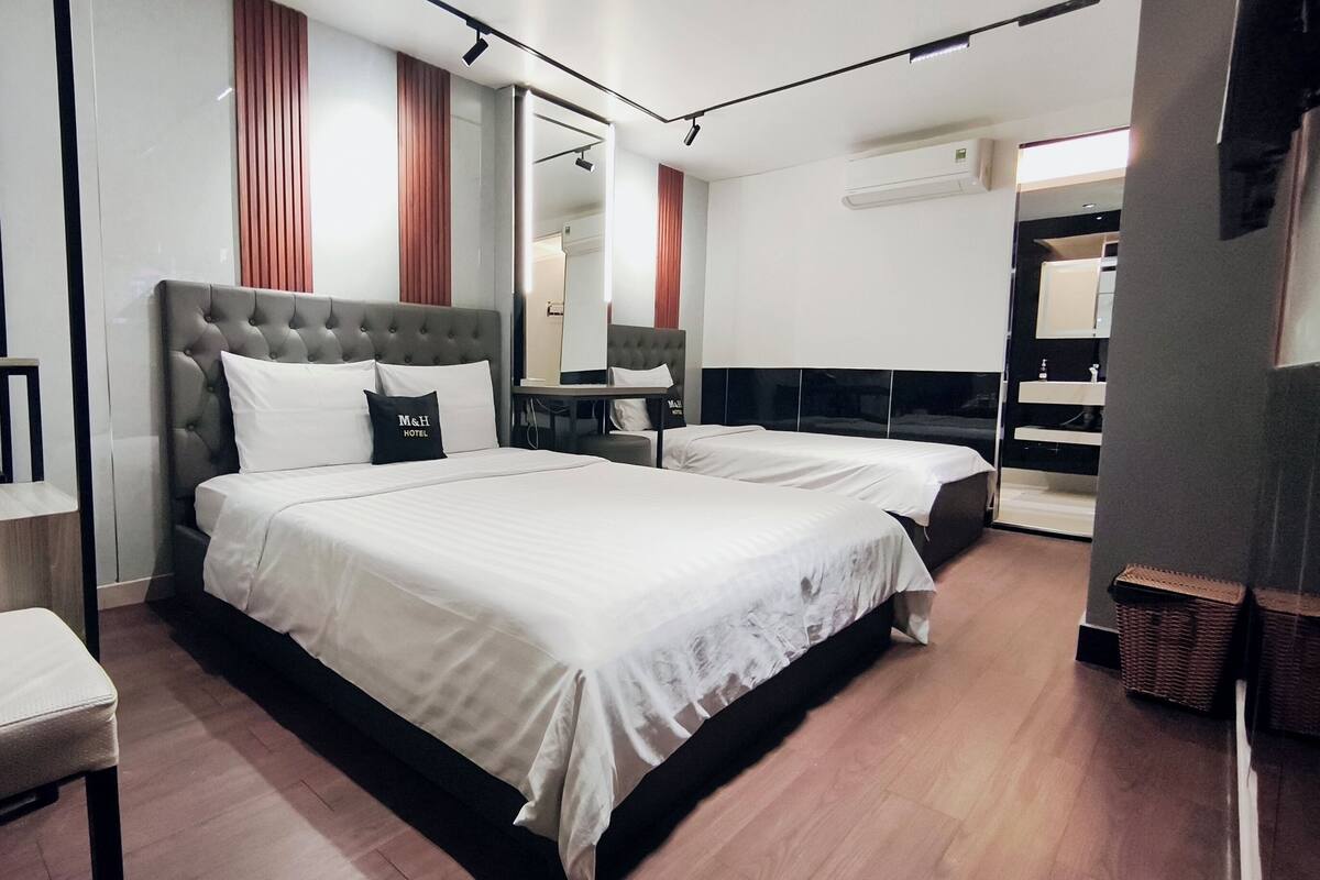 Une chambre d’hôtel avec un grand lit, une table de chevet, une chaise, un bureau avec un ordinateur et un miroir.