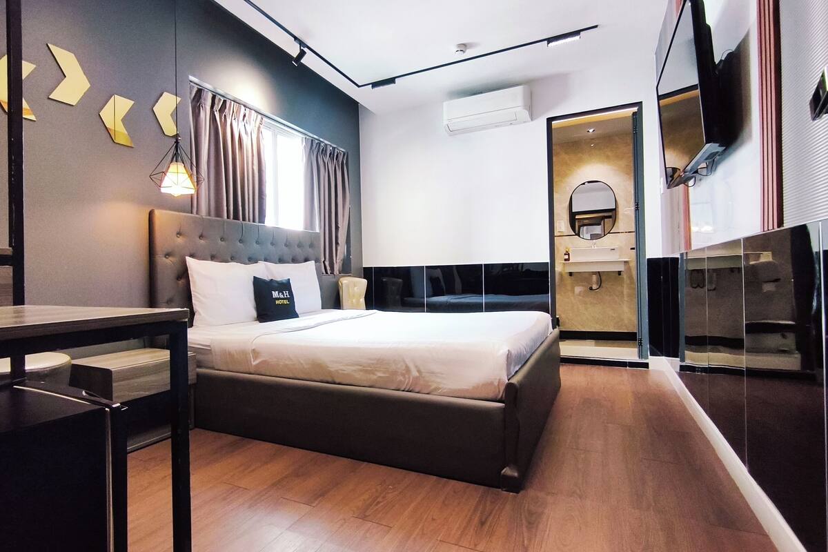 Une chambre d’hôtel moderne avec un grand lit, une table de chevet, un miroir et une armoire.