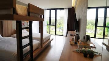 Ein modernes Hotelzimmer mit Etagenbett, einem großen Fenster mit Blick auf Grünflächen und einem Schreibtisch mit Wasserkocher und Pflanze.