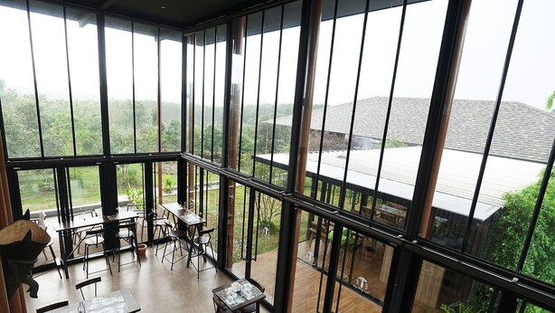 Un vaste espace intérieur doté de grandes fenêtres qui donnent sur un paysage verdoyant et un bâtiment.