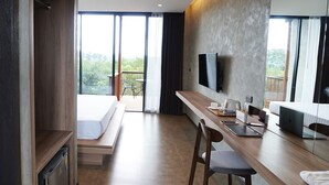 Une chambre d’hôtel moderne dotée d’un grand lit, d’un bureau en bois avec un ordinateur portable, d’une télévision et d’un balcon offrant une vue sur la verdure.