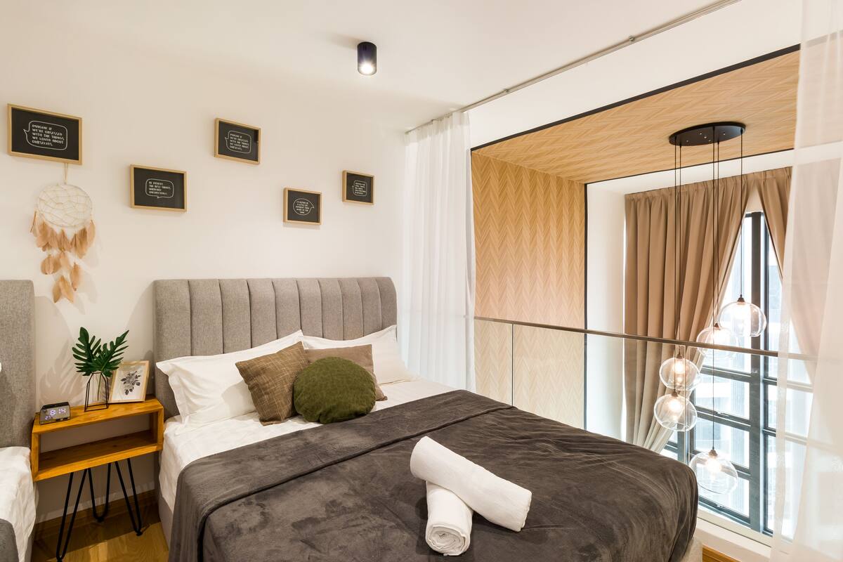 A modern bedroom with a large bed, a bedside table with a plant, and multiple framed quotes on the wall.