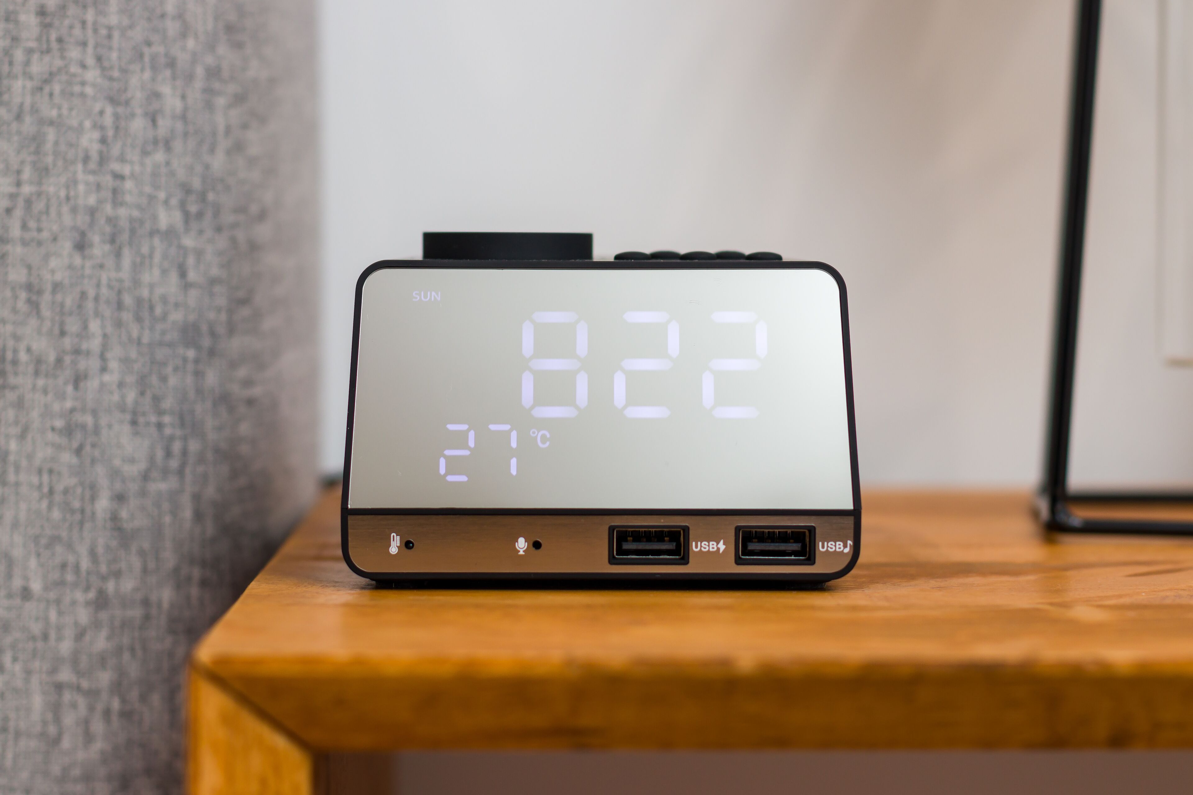 Une horloge numérique affiche l’heure (8h22) et la température (27 °C) sur une surface en bois.