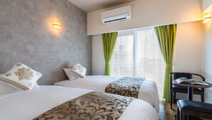 A hotel room with two beds, a small table, a chair, and a window with curtains. - Mr.KINJO in front of Manza Beach (Onna)