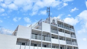 A multi-story hotel with balconies and a clear sky. - Mr.KINJO in front of Manza Beach (Onna)