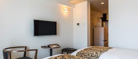 Habitación de hotel con dos camas, un televisor, una mesita y una silla.