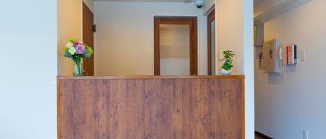 A reception area with a wooden reception desk, a potted plant, and a security camera on the ceiling.