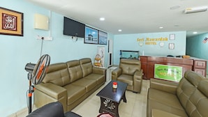A hotel reception area with a reception desk, a sofa, a coffee table, and a fan. - Seri Mawardah Hotel (Malacca City)