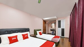 A hotel room with two beds, each with red and white bedding, a green chair, and a wooden floor. - Seri Mawardah Hotel (Malacca City)