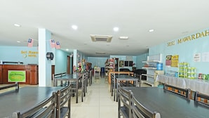 A hotel dining area with multiple tables and chairs, a reception desk, and various amenities like a water dispenser and a self-service counter. - Seri Mawardah Hotel (Malacca City)