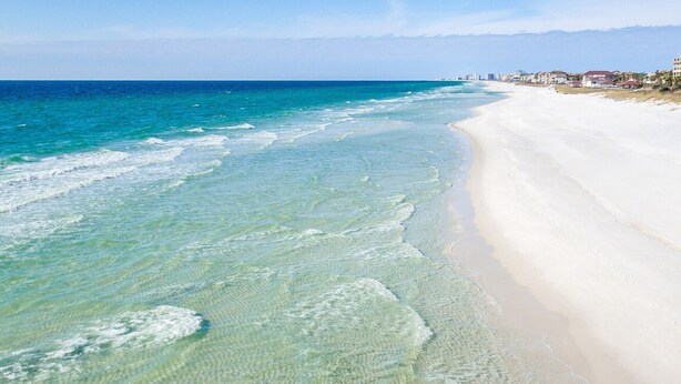 Una playa con aguas poco profundas y cristalinas y una orilla arenosa.