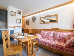 A cozy room with a wooden dining table, chairs, and a patterned sofa.