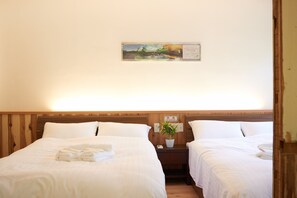 Habitación de hotel con dos camas, cabecera de madera, mesita de noche con una planta y un cuadro en la pared.