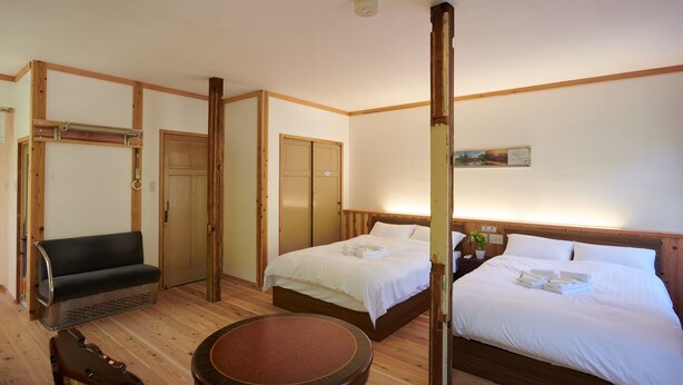 A hotel room with two beds, a wooden bench, a round table, and a small bedside table with a plant. - The Railway Hotel Koyasan Pilgrimage Railway (Kudoyama)