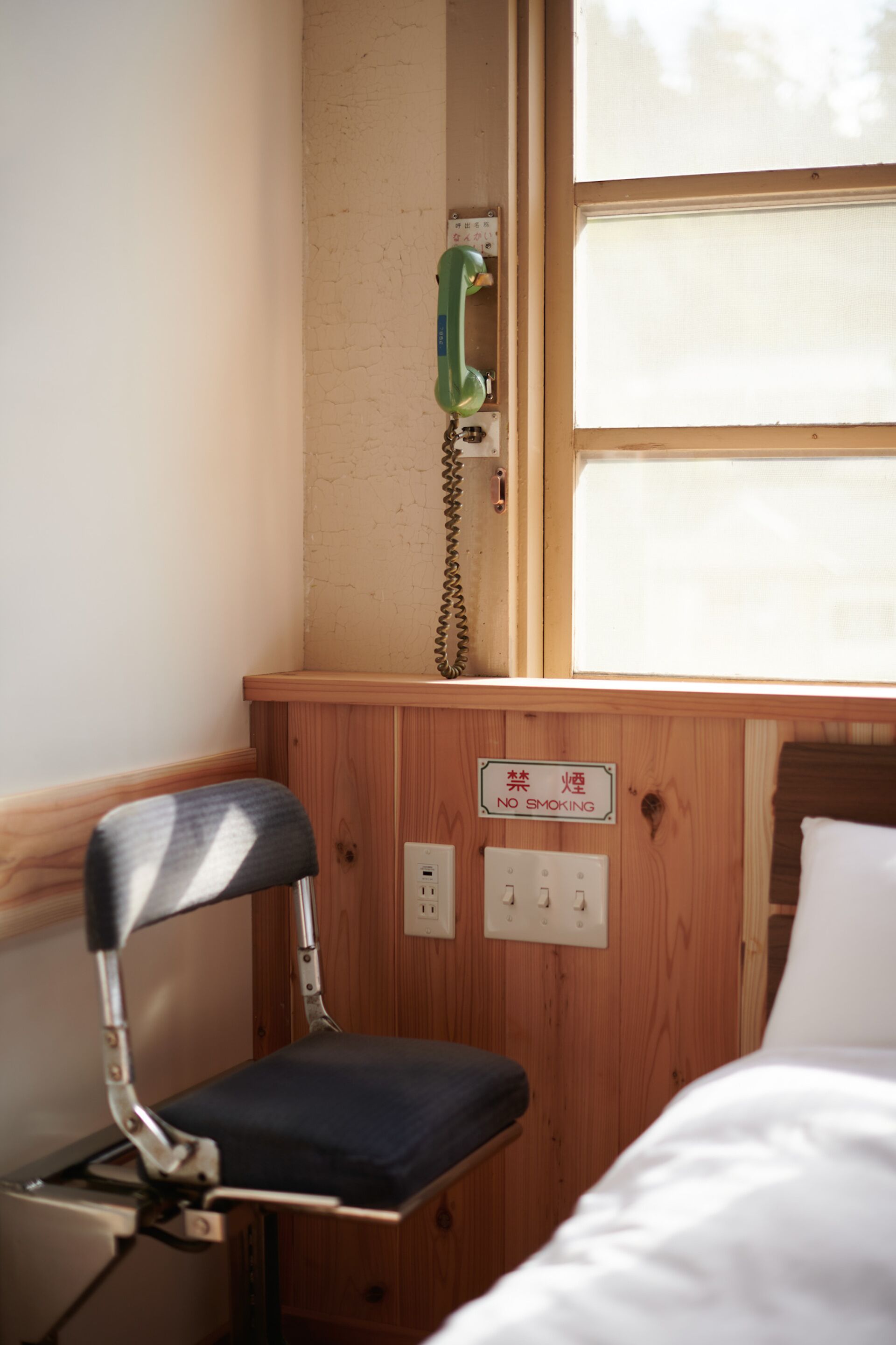 A wooden cabin with a small desk, a telephone, and a bed.