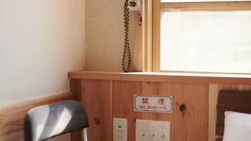 A wooden cabin with a small desk, a telephone, and a bed.