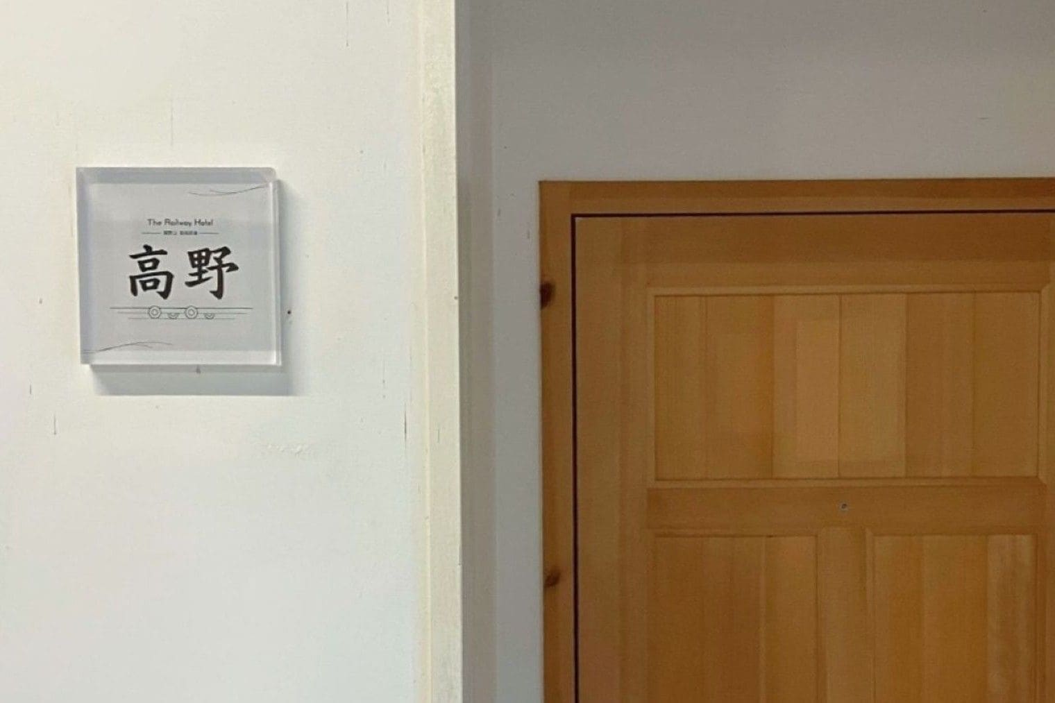 A white wall with a framed sign that reads 'The Railway Hotel' and a wooden door.