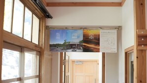 A hallway with wooden doors, a poster with text and images, and a view of a building through the door. - The Railway Hotel Koyasan Pilgrimage Railway (Kudoyama)