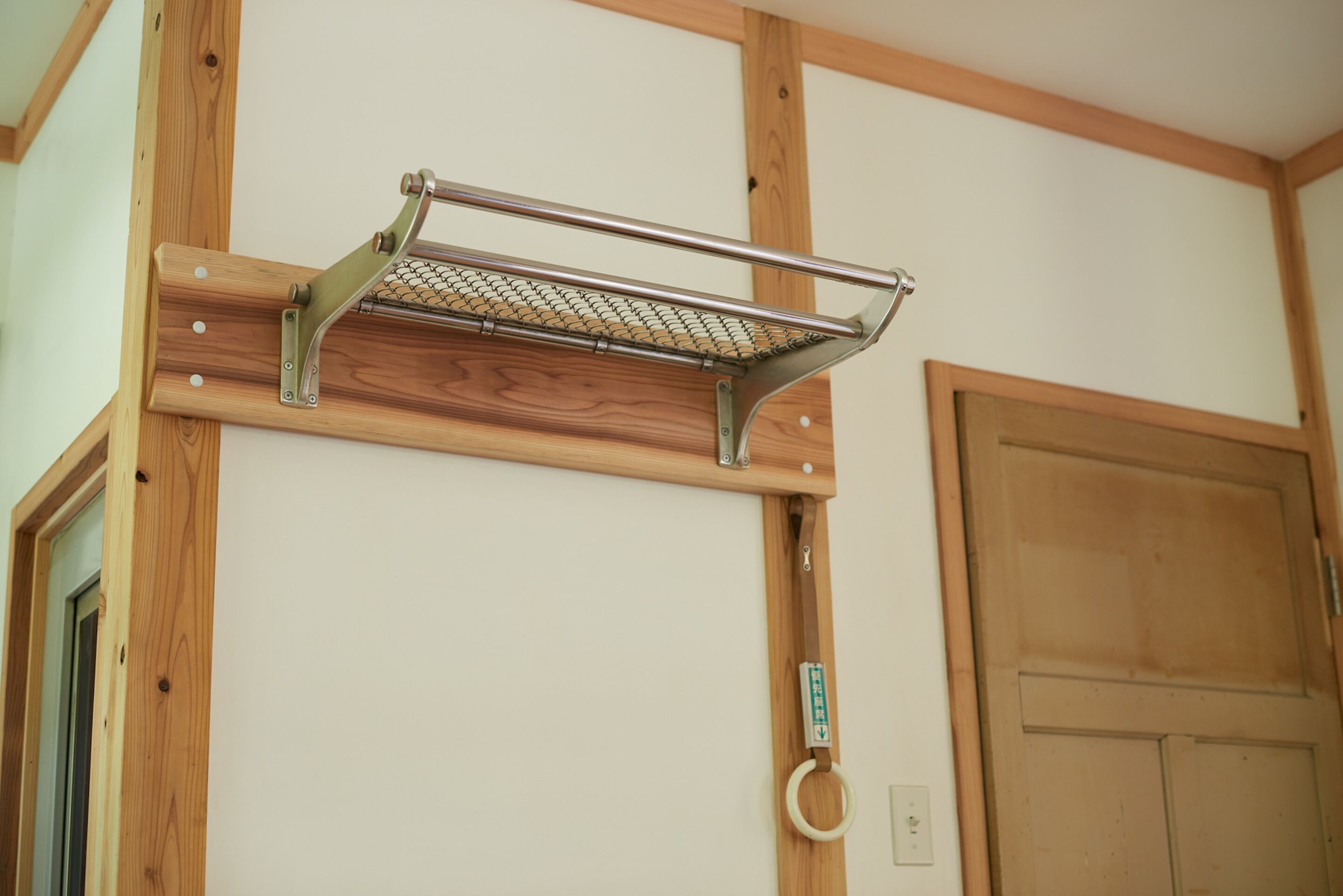 Una estructura metálica con un estante de malla unida a una viga de madera, probablemente para colgar objetos.