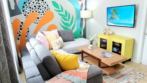 Un salon comprenant un canapé, un pouf, une table basse et un meuble jaune.