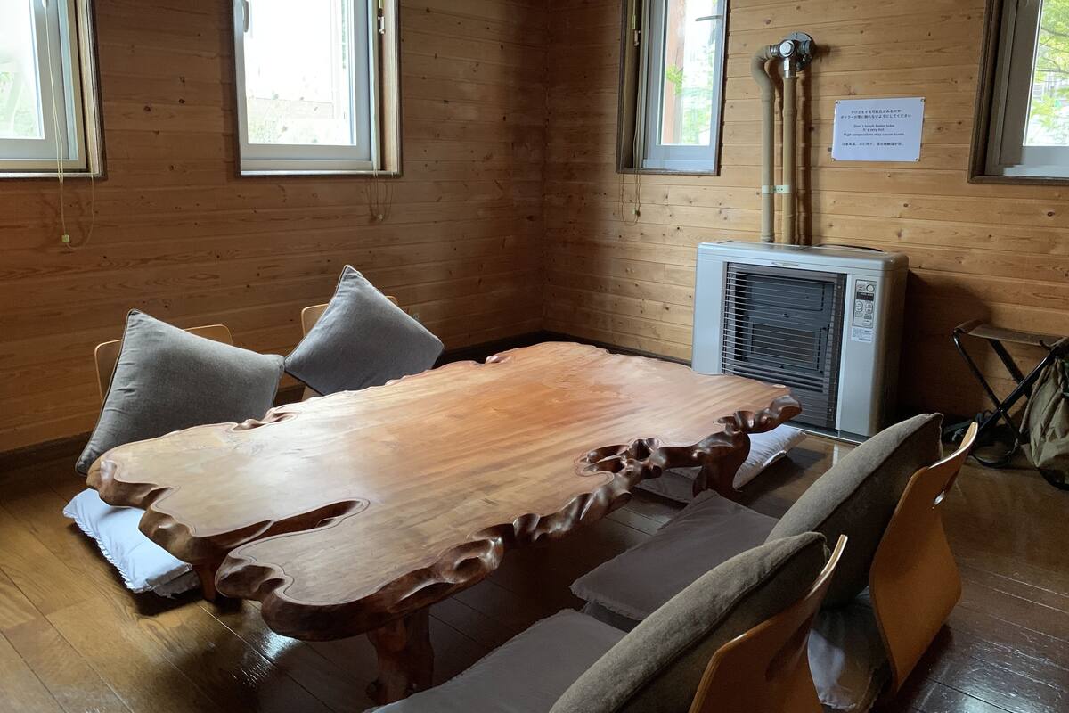 Une pièce aux murs lambrissés, avec une grande table, deux chaises et une fenêtre.