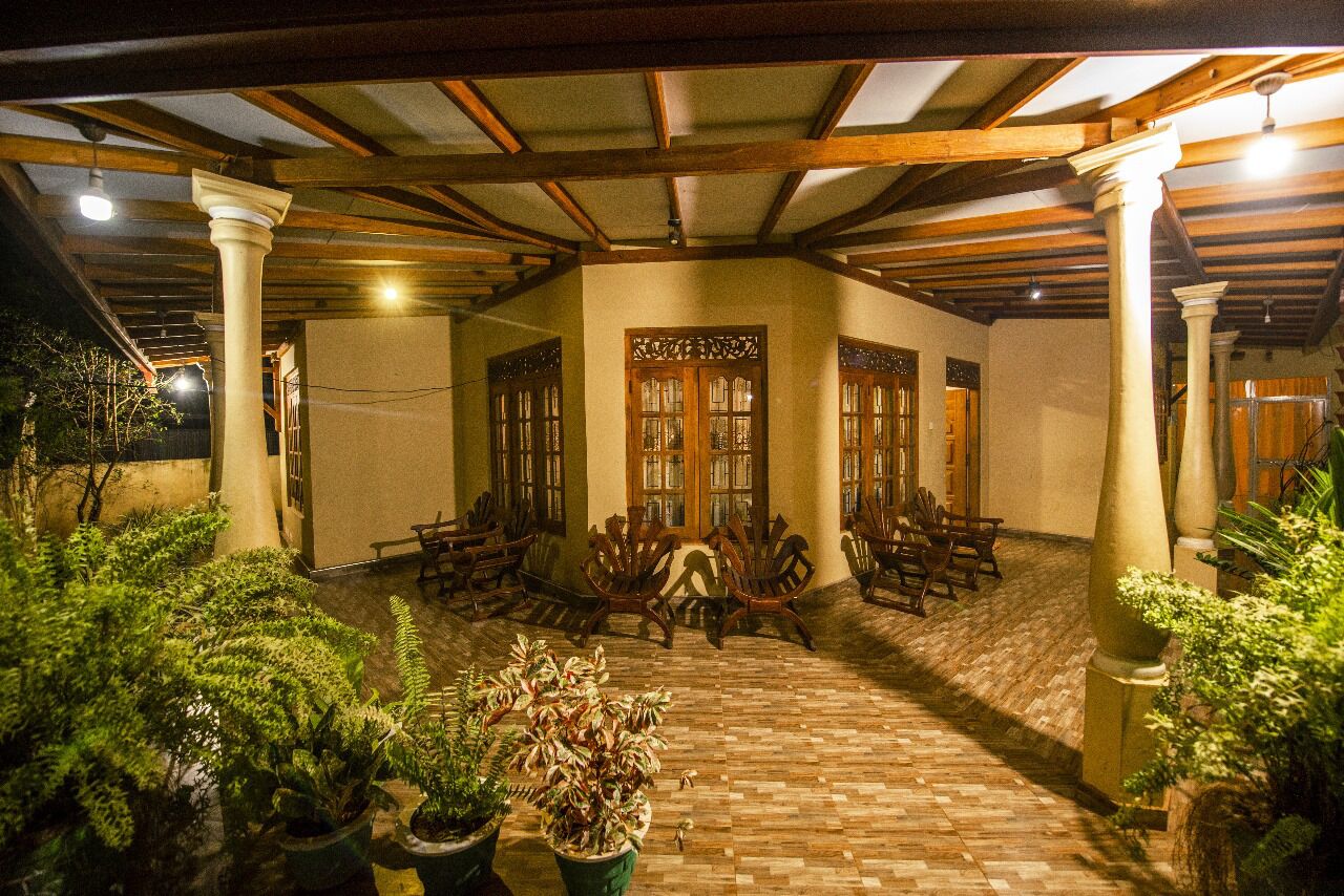 A covered outdoor area with wooden columns, potted plants, and wooden furniture.