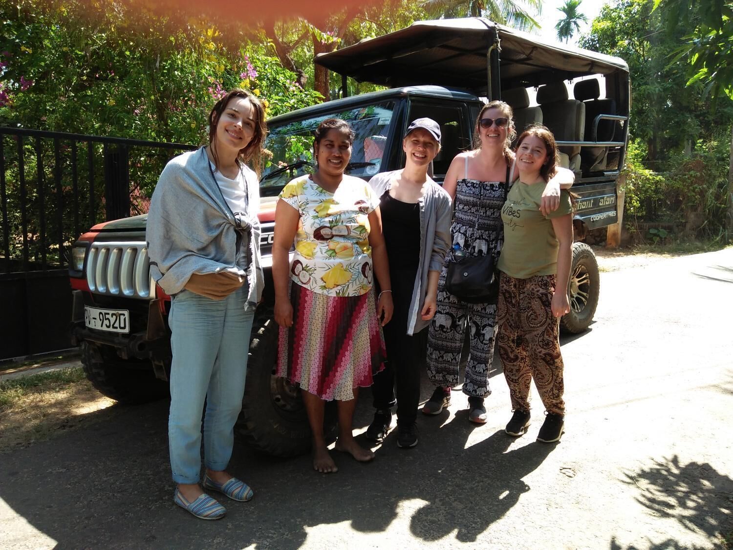 Un grupo de personas frente a un vehículo de safari con una placa de matrícula.