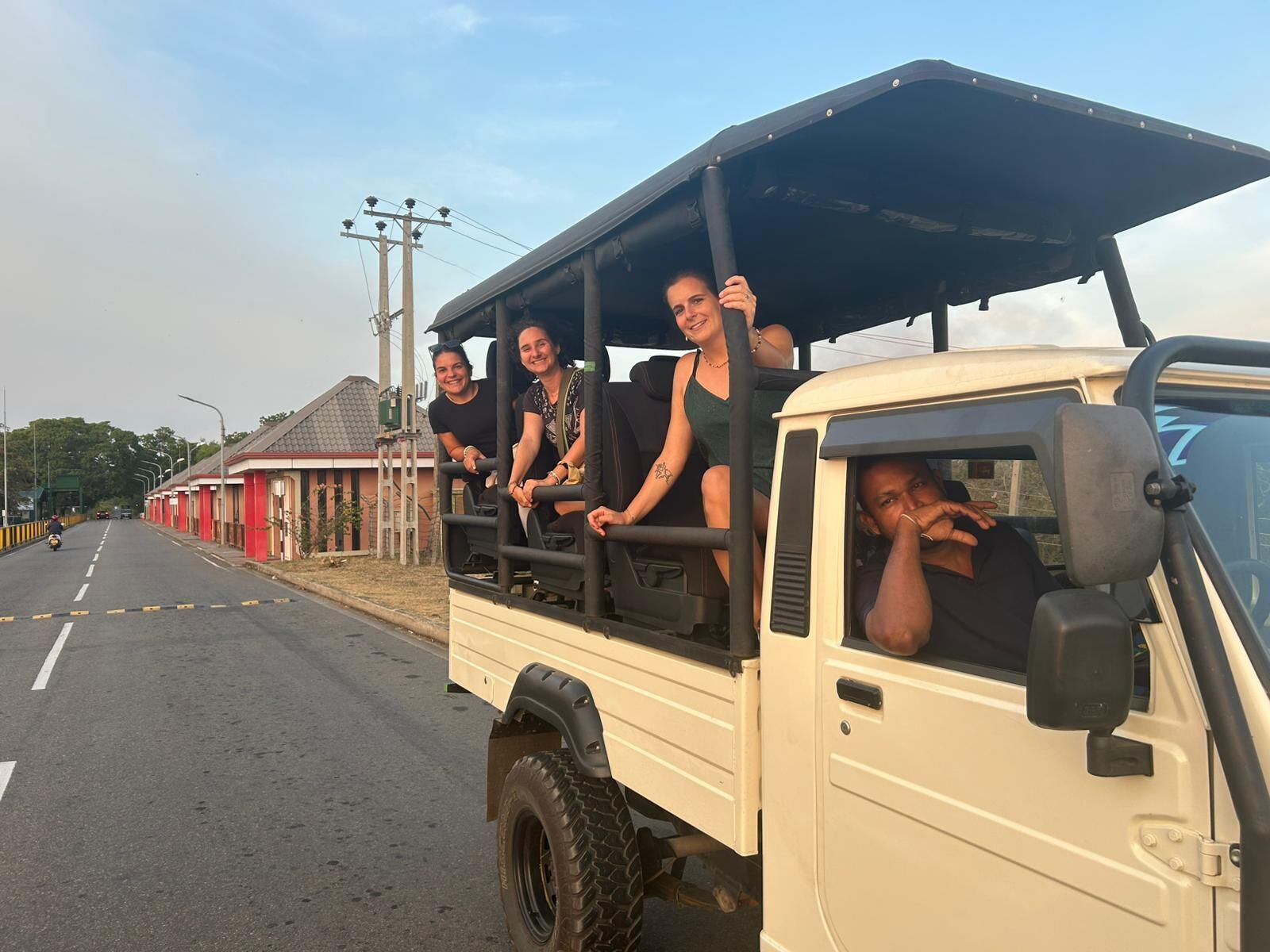 A vehicle with passengers, a road, and buildings in the background.