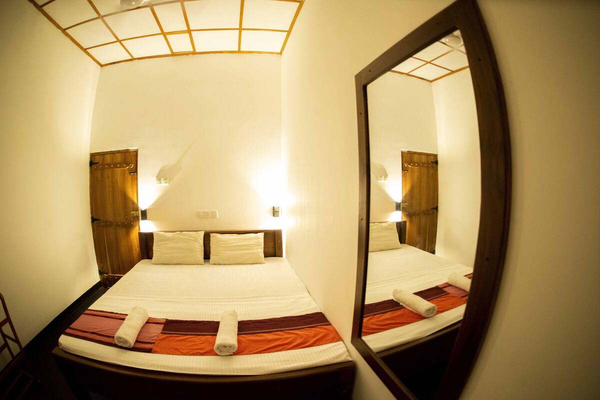 A hotel room with a bed, a mirror, and a headboard.