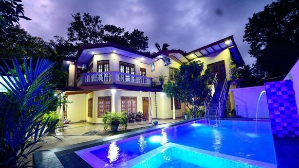 A two-story house with a swimming pool, surrounded by lush greenery and a well-lit exterior. - Wildlife Safari House (Udawalawa)