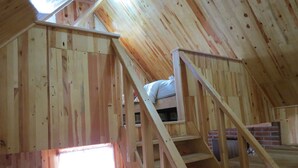A wooden cabin interior with a loft bed, a staircase, and a window. - Viña Real Cabañas Rotamundos (Tacambaro)