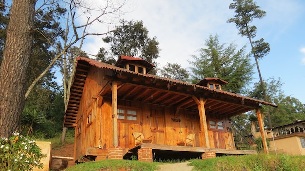 A wooden cabin with a porch, steps leading up to it, and a natural surrounding. - Viña Real Cabañas Rotamundos (Tacambaro)