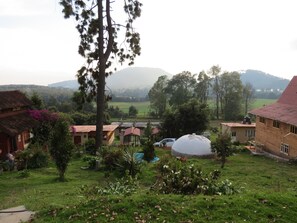 A rural village with traditional houses, a large water tank, and a view of distant hills. - Viña Real Cabañas Rotamundos (Tacambaro)