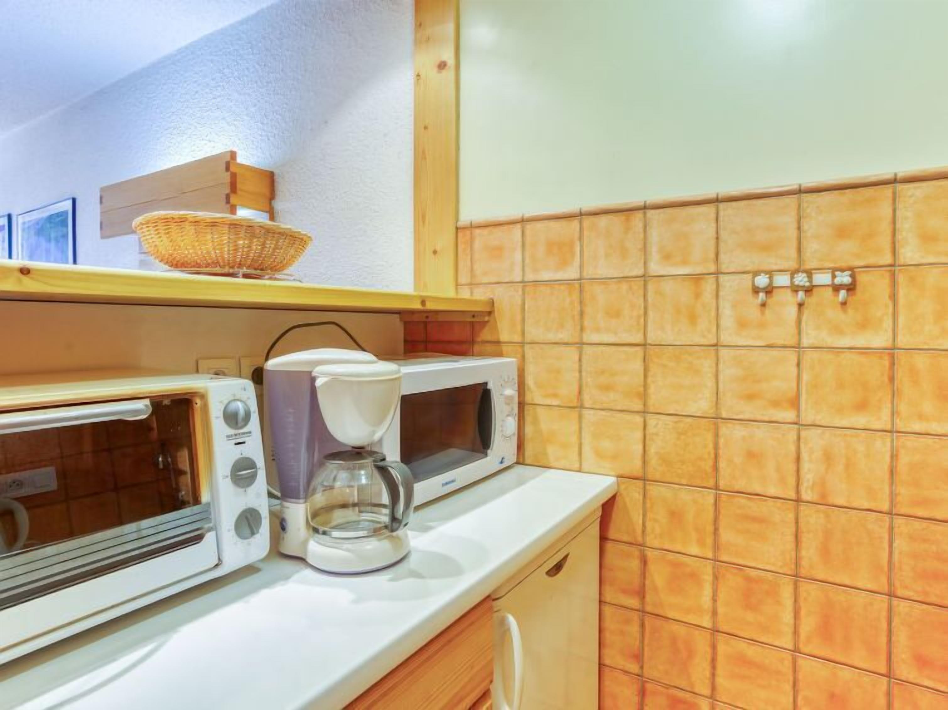 A kitchen with a toaster, coffee maker, and microwave.