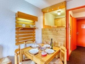 A wooden dining table with chairs, a mirror above it, and a red door in the background.