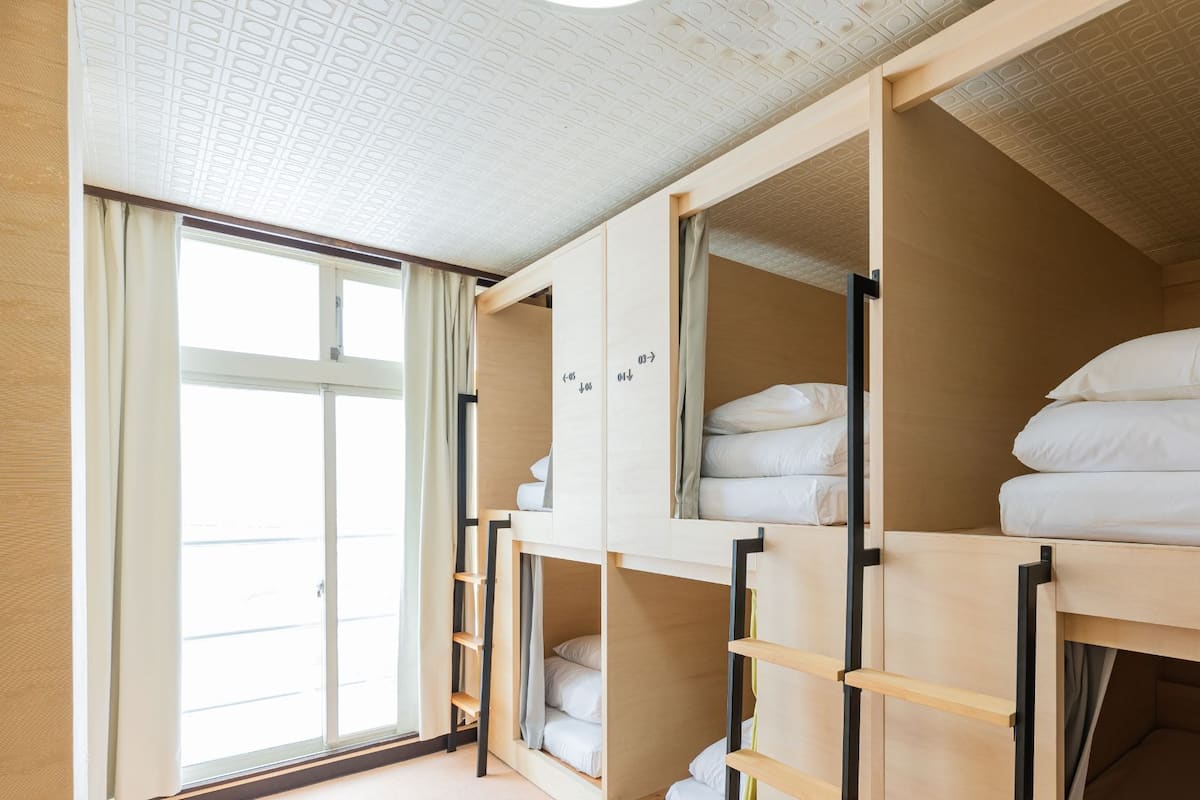 Ein Schlafsaalzimmer mit Etagenbetten, einem Fenster und einer Decke mit geometrischem Muster.