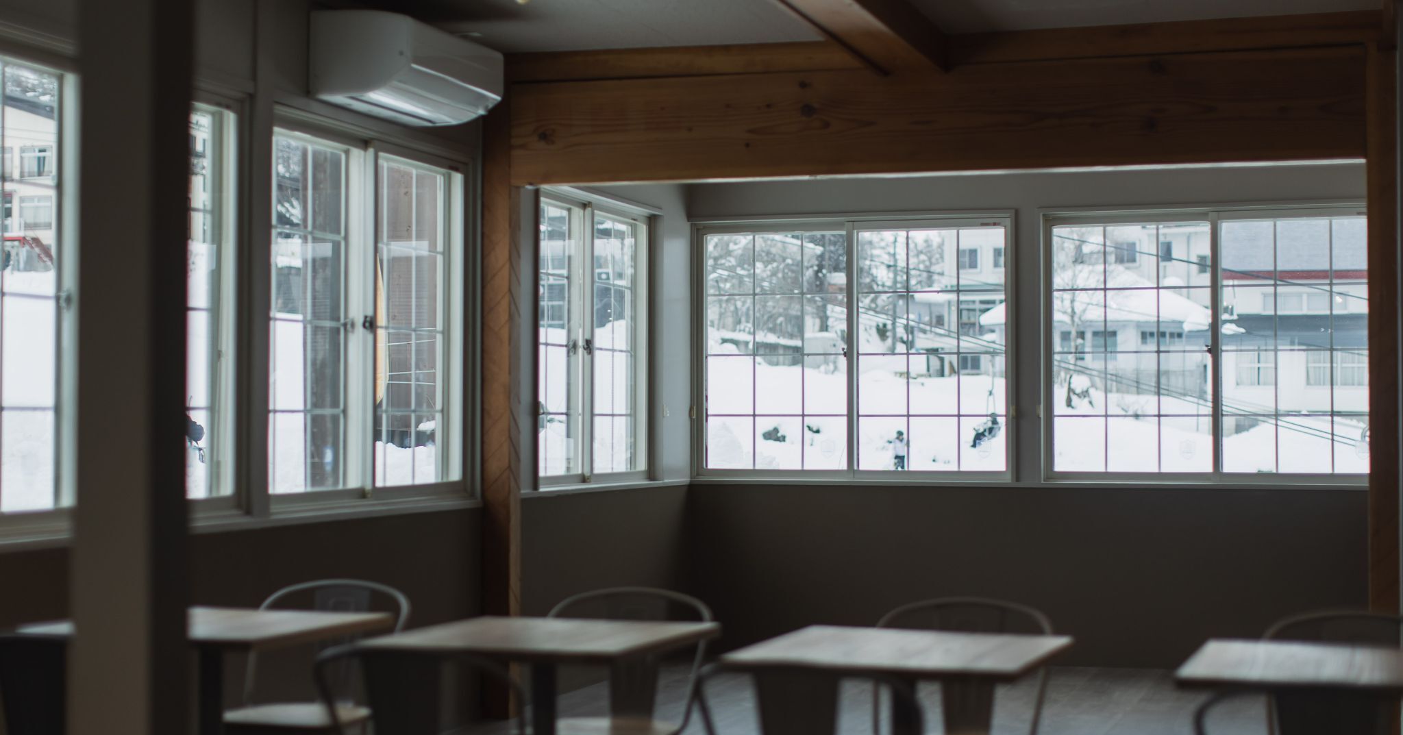 A room with large windows, wooden walls, and several tables and chairs.