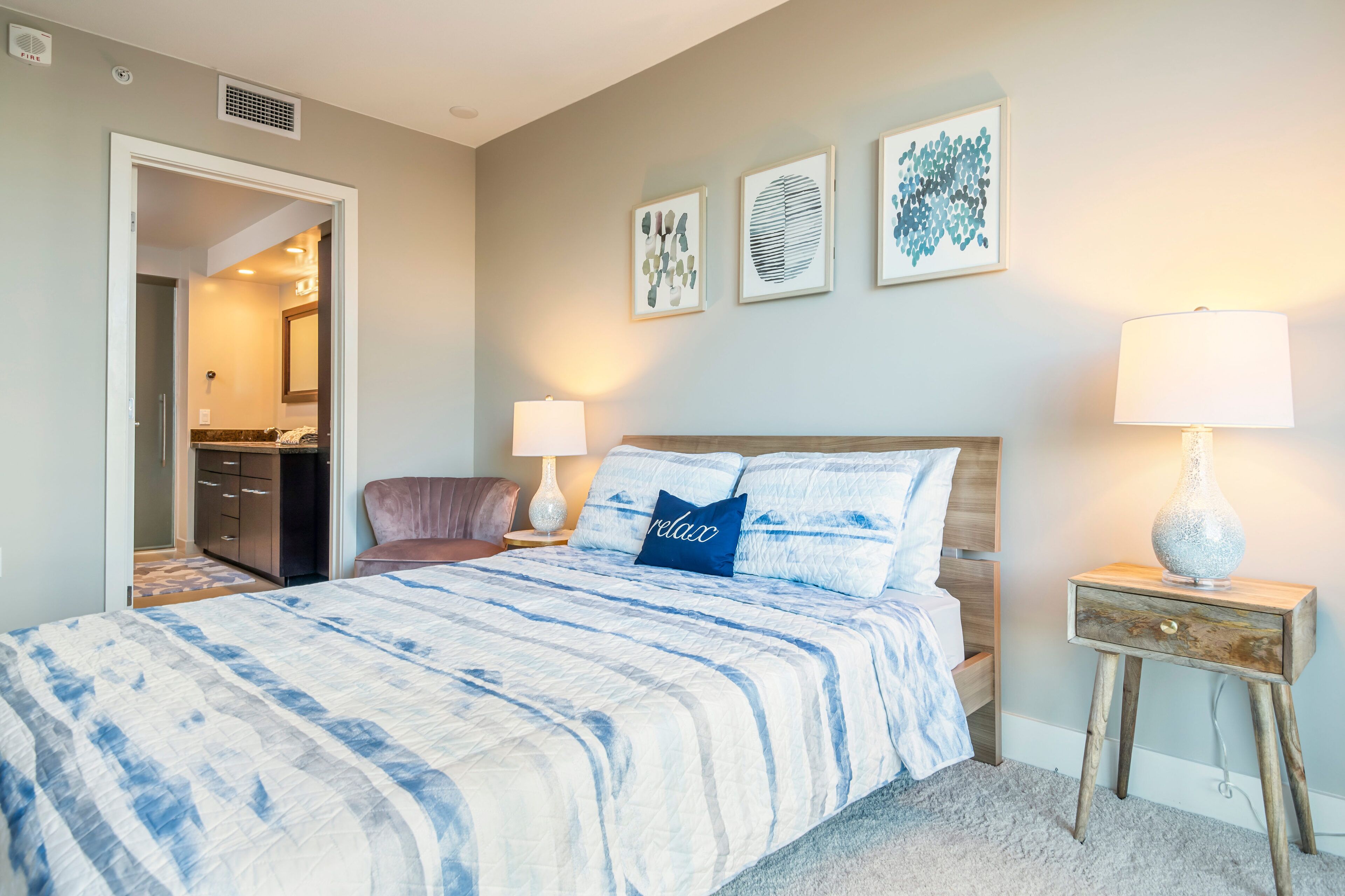 A bedroom with a bed, bedside lamps, a nightstand, and artwork on the wall.