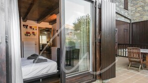 Ein Schlafzimmer mit Bett, einem hölzernen Stuhl und einem Tisch auf einer Terrasse.