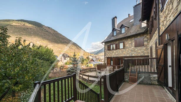 Ein Steinhaus mit Balkon und Blick auf eine gebirgige Landschaft.